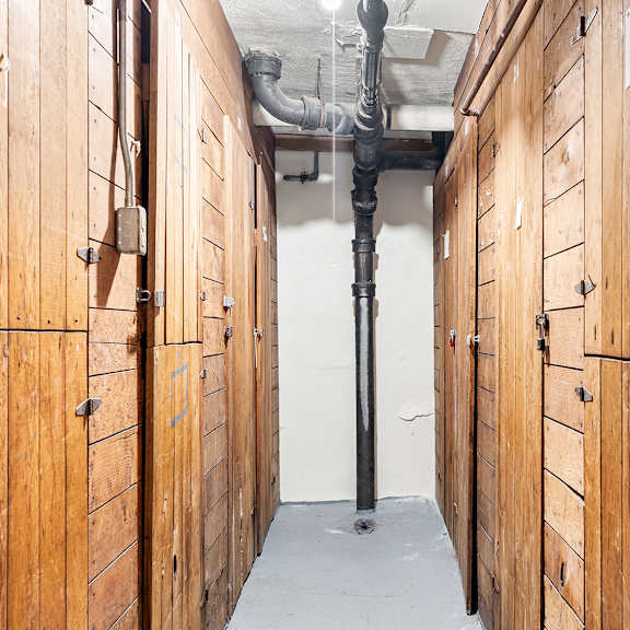a long hallway with wood paneling and pipes on the ceiling.