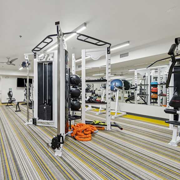 a gym with a striped carpet and a variety of equipment.