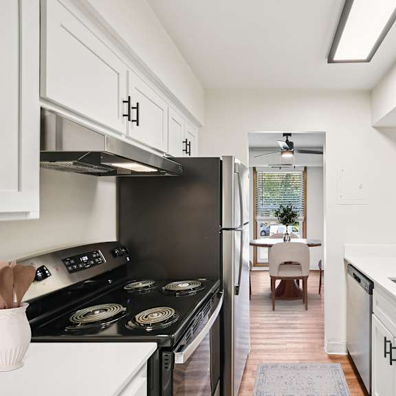 a modern kitchen with a black stove top oven and white cabinets.
