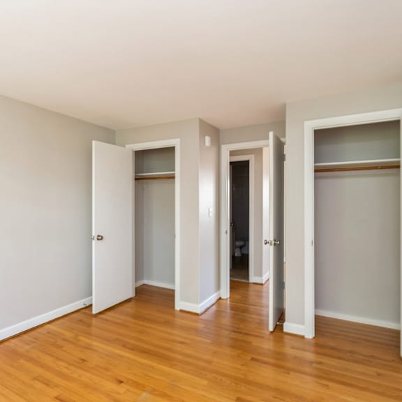 an empty bedroom with wood floors and closet doors