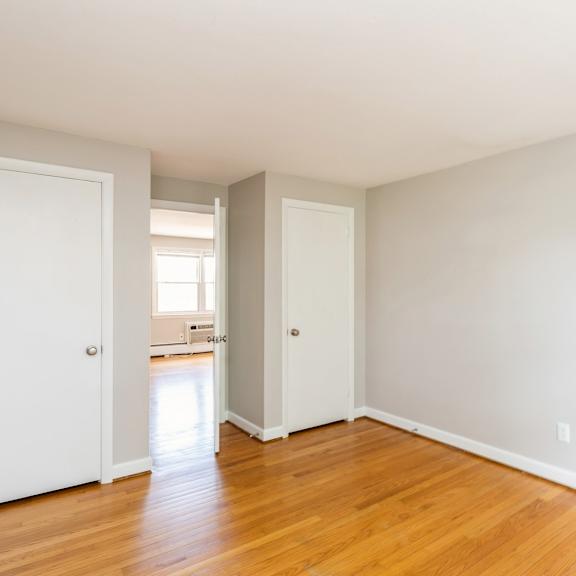 an empty bedroom with wood floors and white doors
