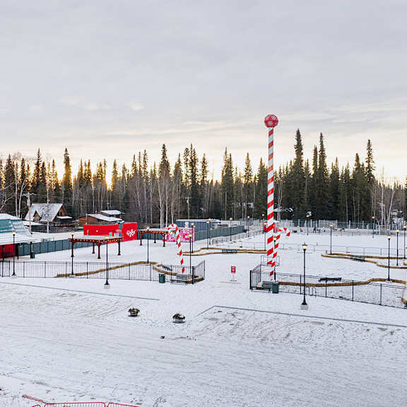 a snowy landscape with a red and white striped pole in the foreground.