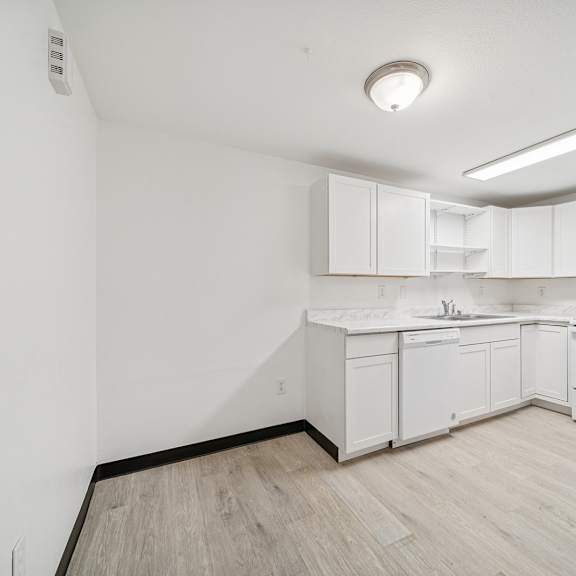 a white kitchen with a wood floor and white cabinets.