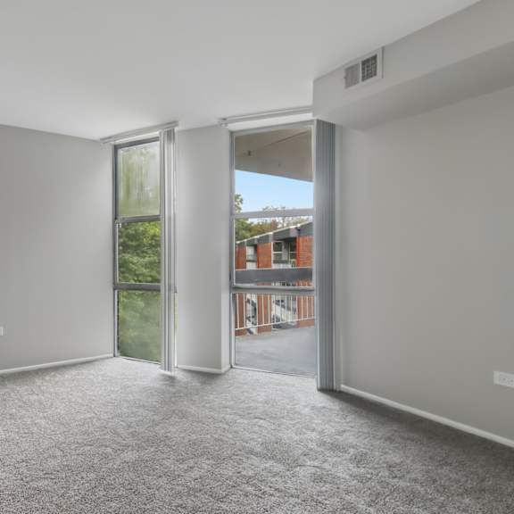 a room with grey carpet and a sliding glass door leading outside.