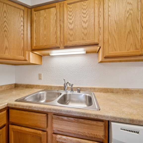 a kitchen with wooden cabinets and a stainless steel sink.