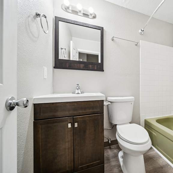 a white toilet sits next to a green bathtub in a bathroom.