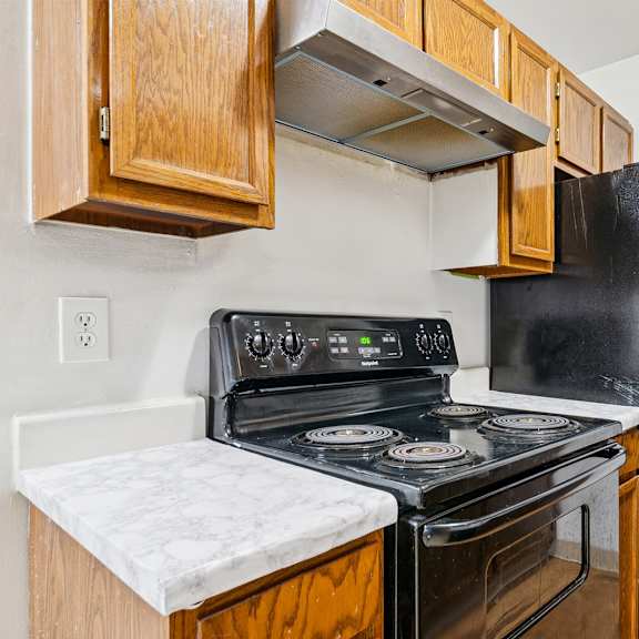 a black stove and refrigerator in a kitchen with wooden cabinets.
