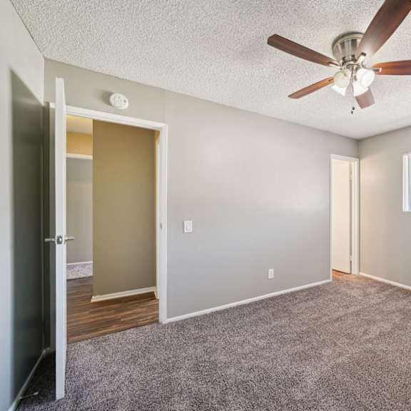 a room with a ceiling fan and a window with blinds.