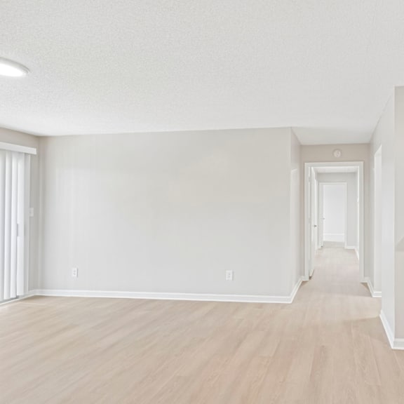 a long hallway with white walls and wood floors.