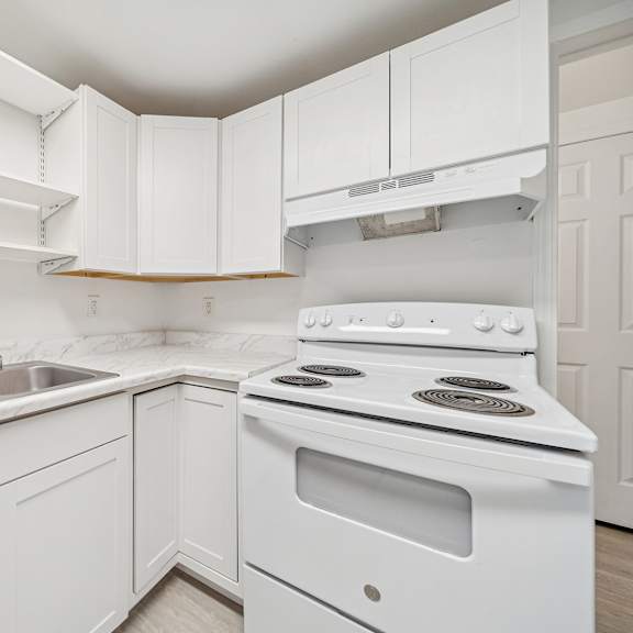 a white kitchen with a stove and sink.