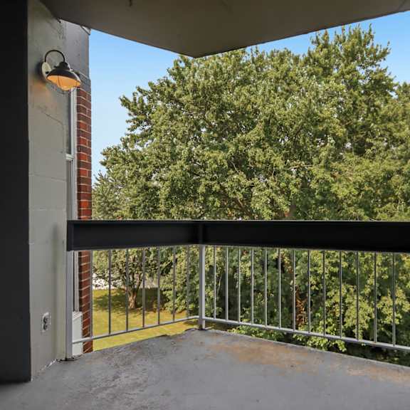 a balcony with a metal railing and a view of trees.