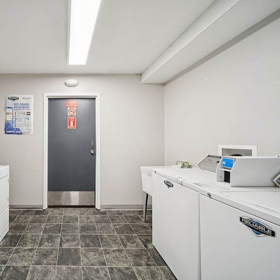 a clean, white-walled kitchen with a stainless steel refrigerator and a tiled floor.