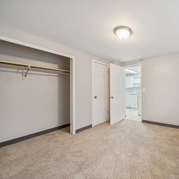 a room with a carpeted floor and a window with blinds.