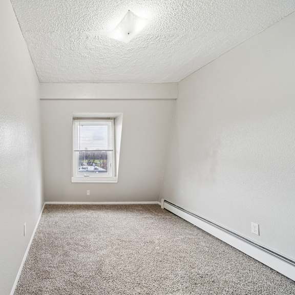 a small, empty room with a carpeted floor and a window.