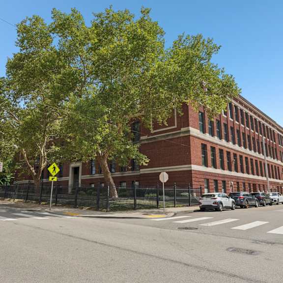 a street view with a red brick building, cars, and trees.