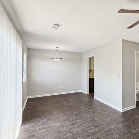 a room with a ceiling fan and wooden flooring.
