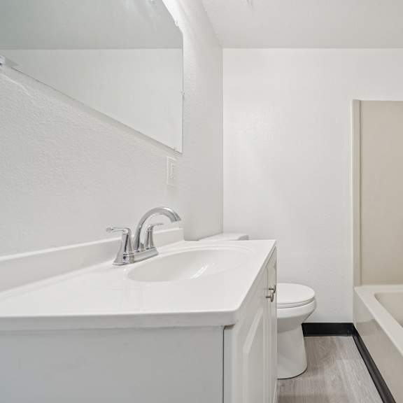 a white bathroom with a sink, toilet, and bathtub.