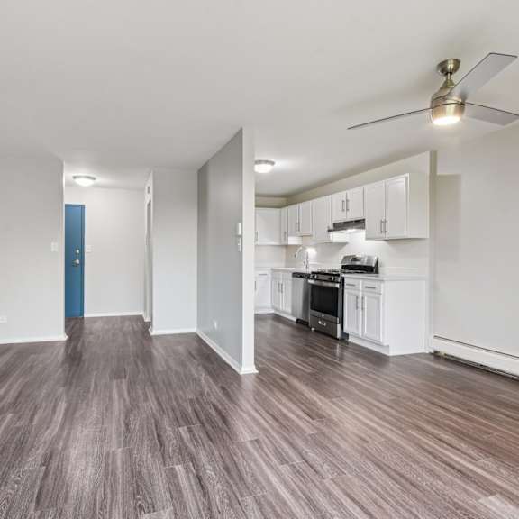 a room with a kitchen area and a wood floor.