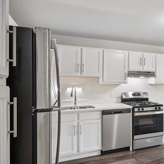 a kitchen with white cabinets and stainless steel appliances.
