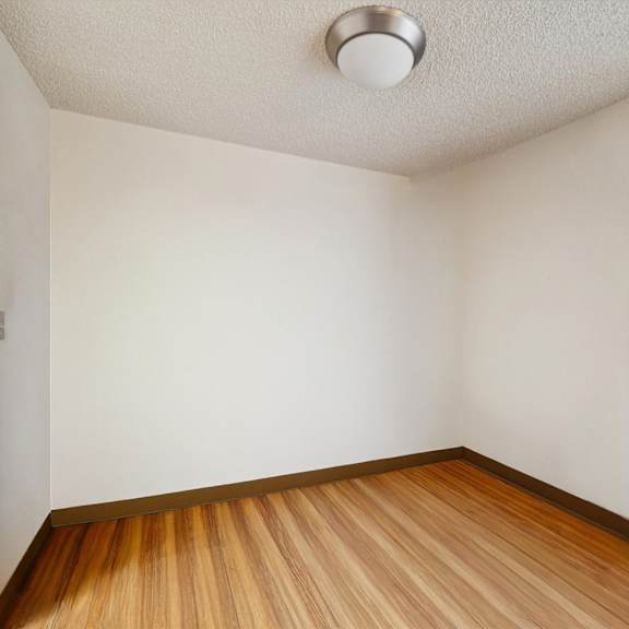 a room with wooden flooring and a window with blinds.