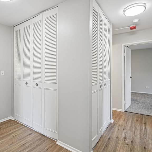 closet with white doors and wood floors.