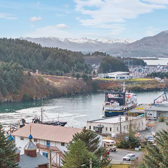 a view of a town with a river and mountains in the background.