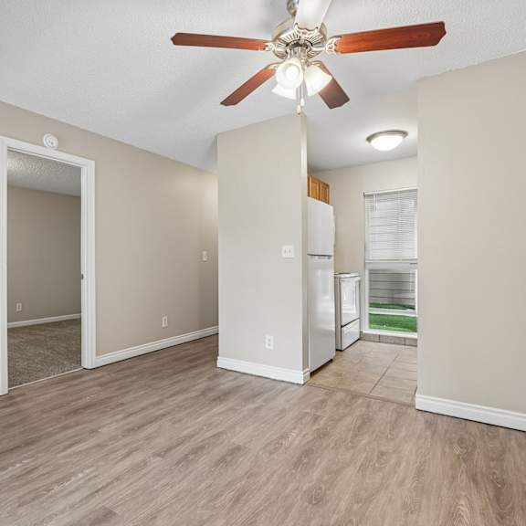 a room with a ceiling fan and a refrigerator.