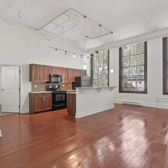 a large living room and kitchen with wooden floors and white walls.