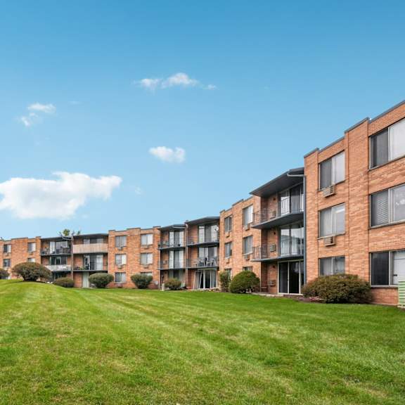 a row of apartment buildings with a green lawn in front.