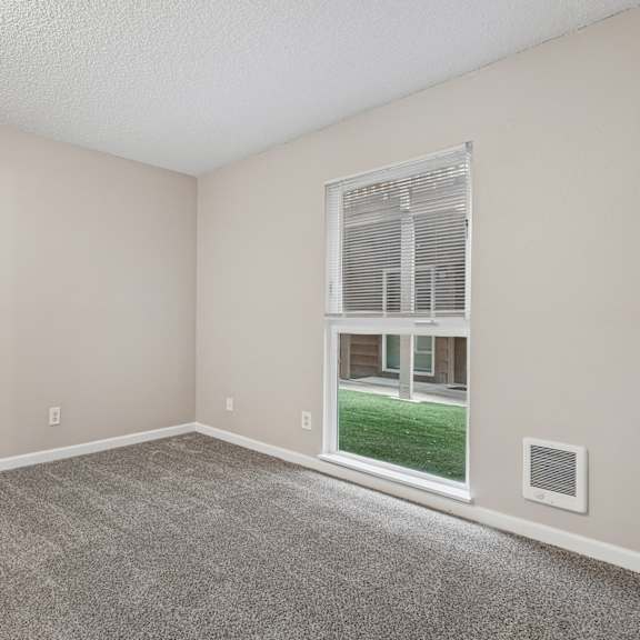 a room with a carpeted floor and a window showing a view of a building outside.
