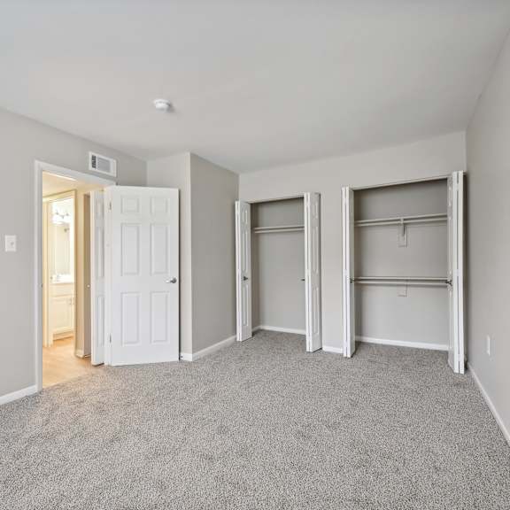 a bedroom with a carpeted floor and two closet doors at renew odenton
