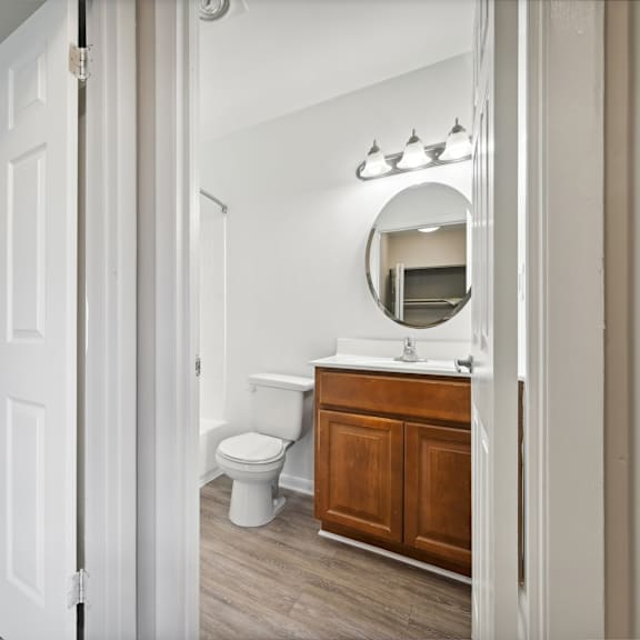 a bathroom with a toilet and a vanity with a mirror at renew odenton