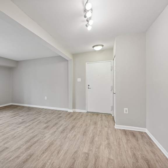 an empty living room with white walls and wood flooring at renew odenton