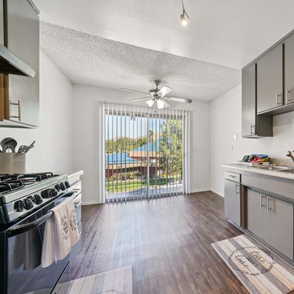 a kitchen with a black refrigerator and wooden floors.