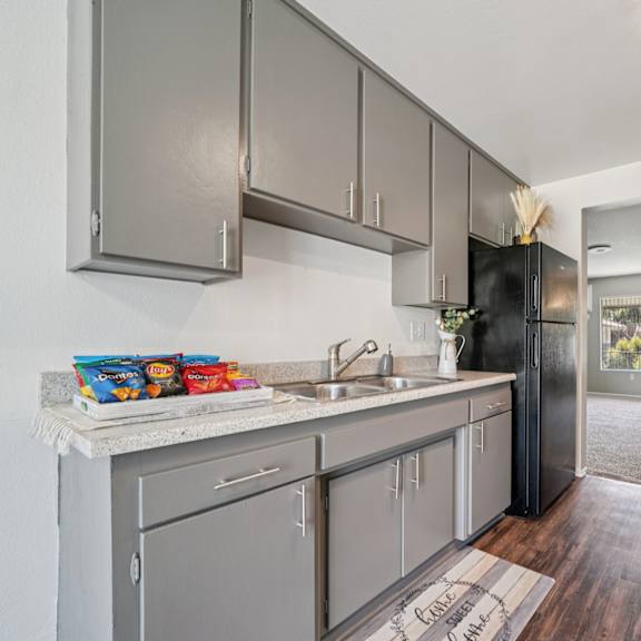 a kitchen with a black refrigerator and wooden floors.