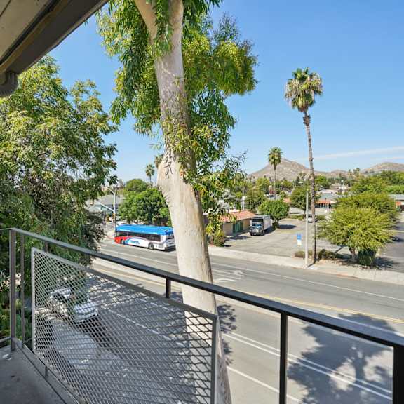 a view from a balcony overlooking a street with cars and palm trees.