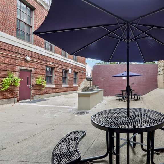a purple umbrella is open over a table with two chairs.
