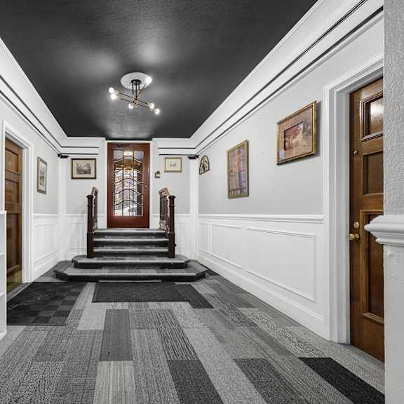 a hallway with a clock on the wall and a staircase in the background at pleasant oak apartments, oak park