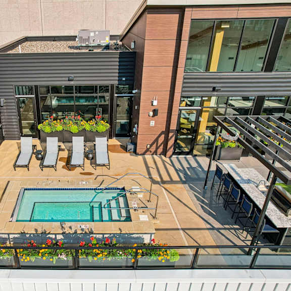 a small pool is surrounded by a deck with chairs and flowers.
