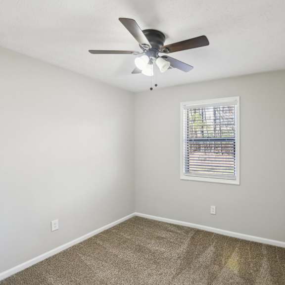 a room with a ceiling fan and a window with blinds.