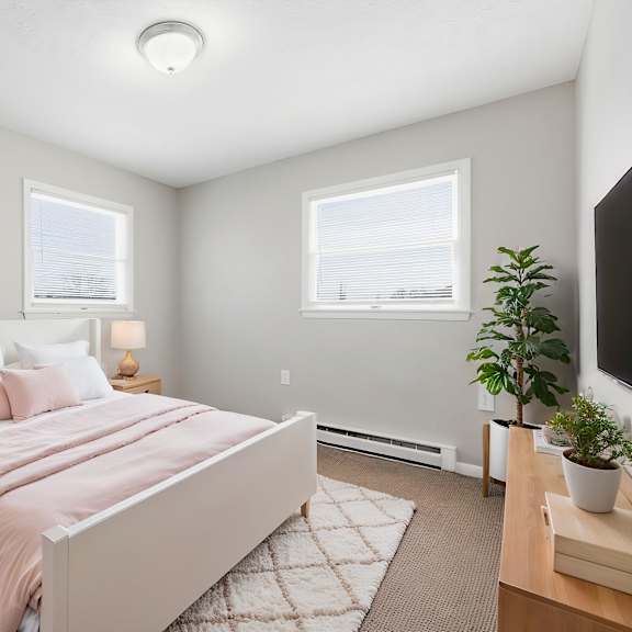 a bedroom with a bed, nightstands, and a plant.