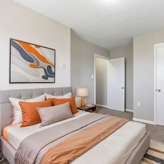 a bedroom with a bed, nightstand, and a painting on the wall.