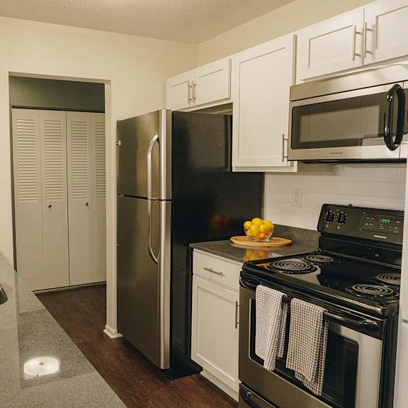 a kitchen with a black refrigerator and stove top oven at astor place of edina apartments , edina, mn