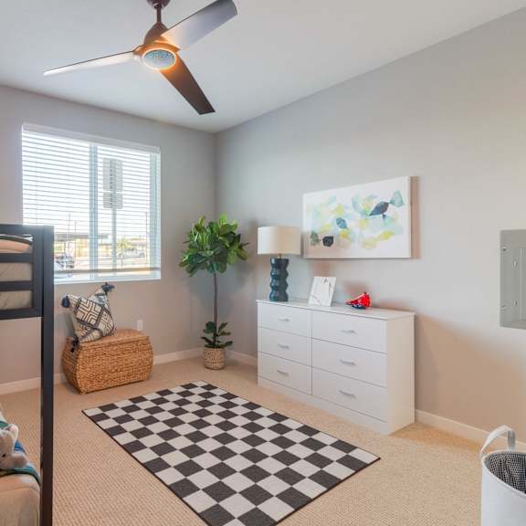 a bedroom with a bed, a ceiling fan, a dresser, and a rug.