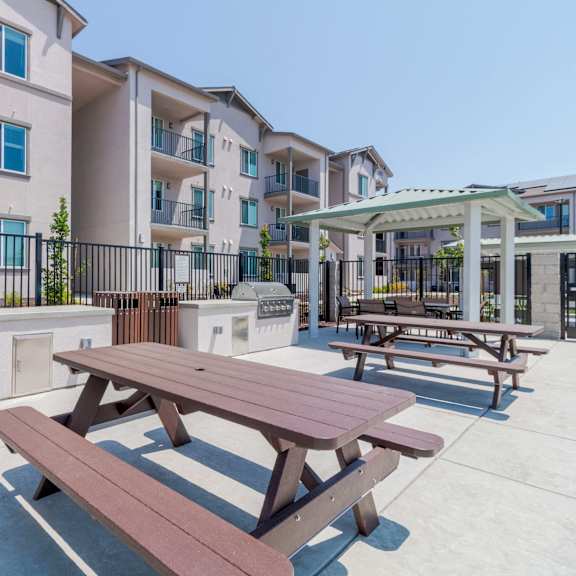 a picnic table is in the foreground of a courtyard with apartment buildings in the background.