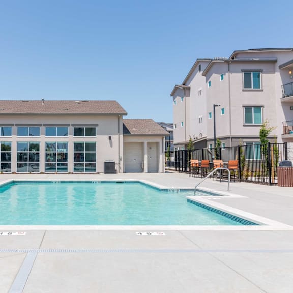 a large swimming pool in front of a building with a clear blue sky above.