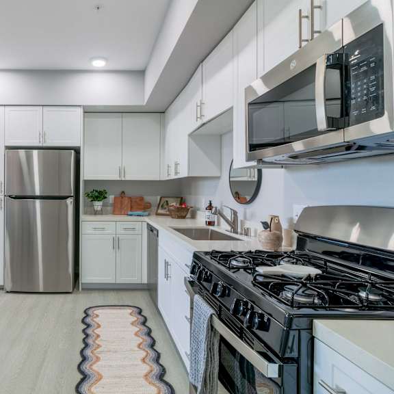 a modern kitchen with a stainless steel refrigerator and a black microwave above the stove.