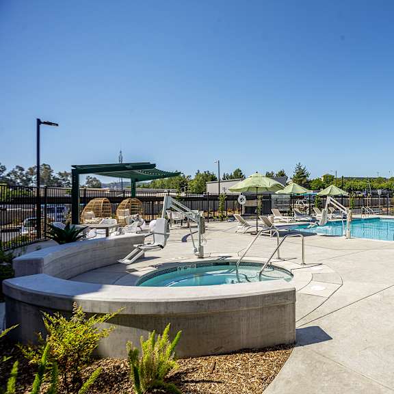 a large outdoor swimming pool with a hot tub and lounge chairs.