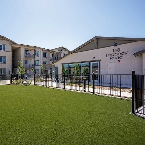 a grassy dog park in front of an apartment building