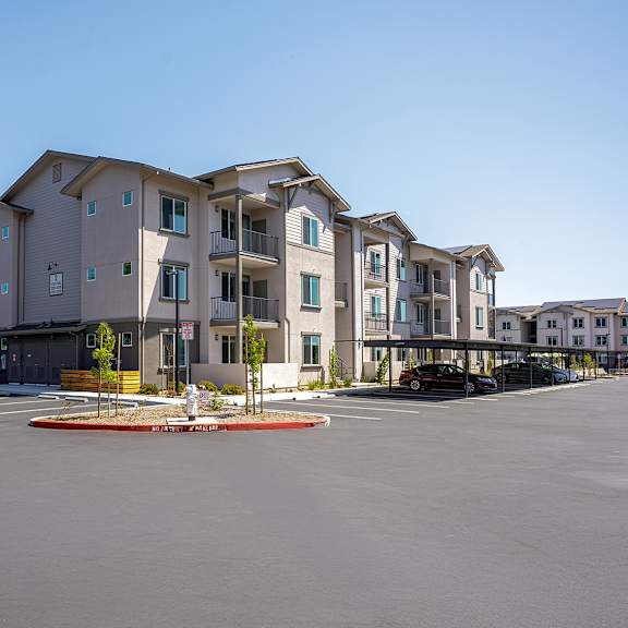 a large apartment building with a parking lot in front of it.